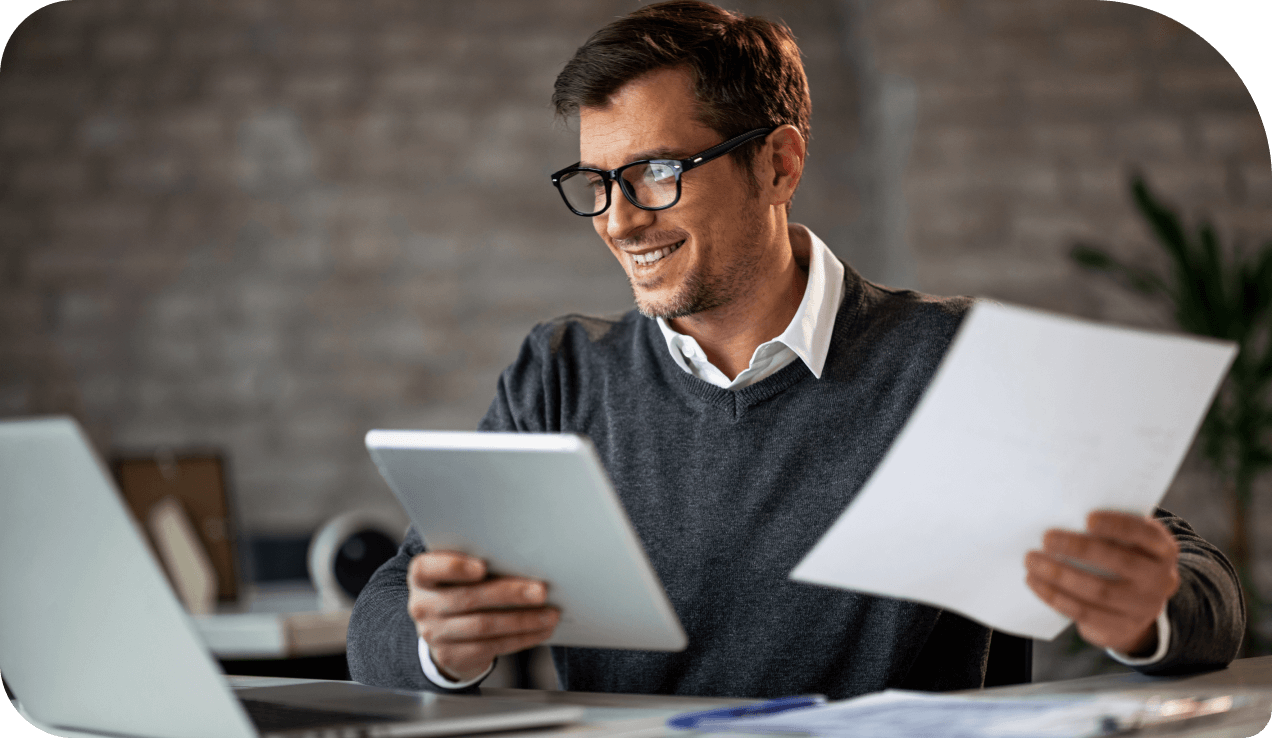 Homem de óculos segurando folhas em um escritório